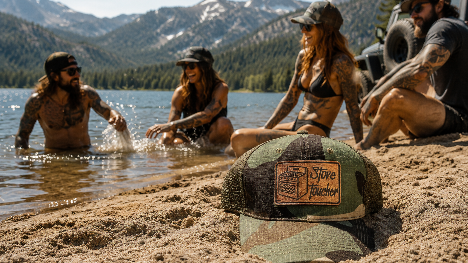 A green and brown camouflage trucker hat with a 'Stove Toucher' logo patch sits in the sand in the foreground, with four people relaxing by a lake and snow-capped mountains in the background.