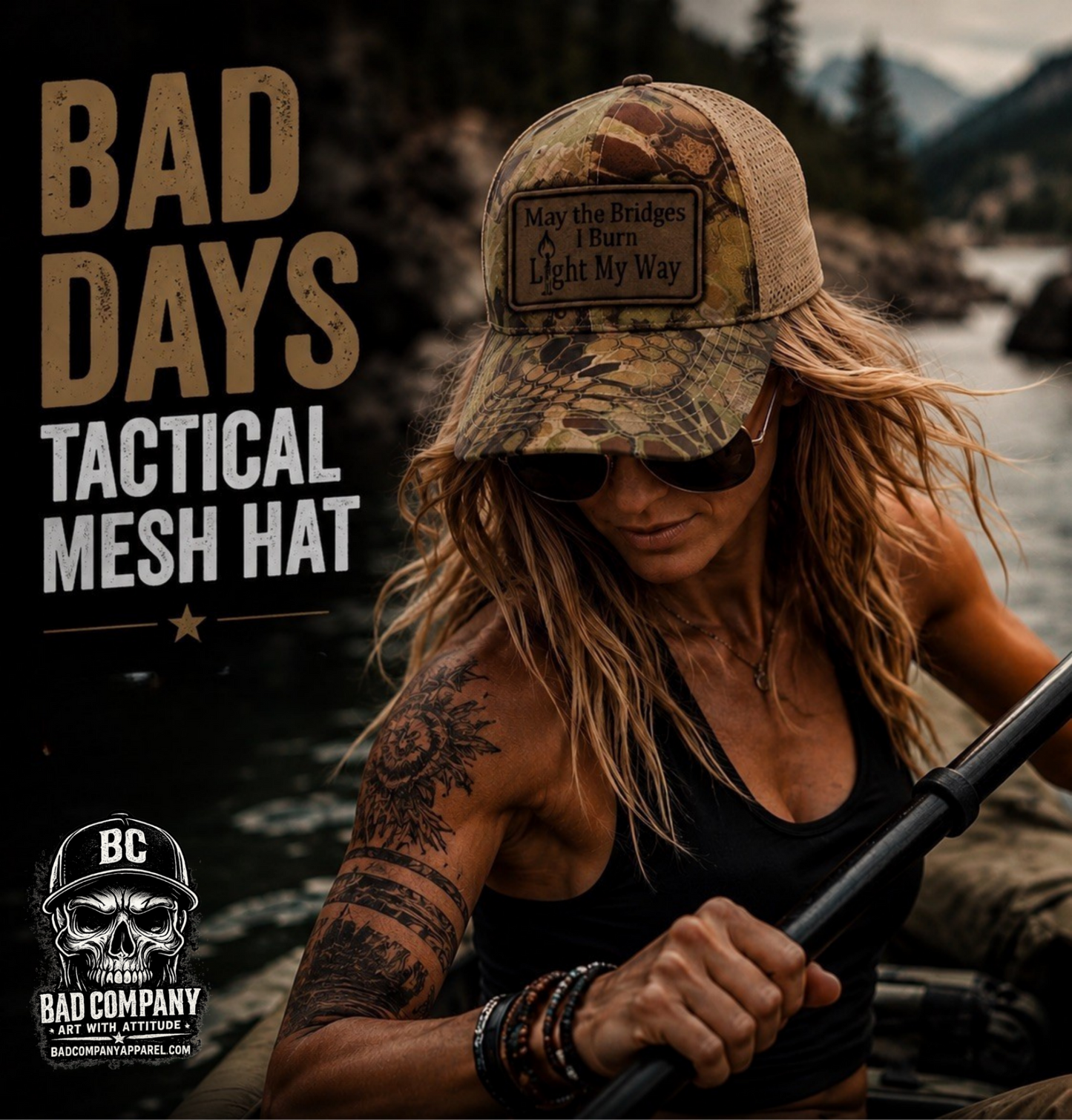 A woman in a black tank top and sunglasses paddles on a lake while wearing a camouflage trucker hat with a brown patch that reads "May the Bridges I burn Light my Way" Large text on the left says 'BAD DAYS TACTICAL MESH HAT,' and the Bad Company logo appears in the lower left.